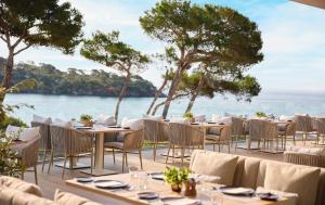 a restaurant with tables and chairs and a view of the ocean at Ikos Porto Petro in Portopetro