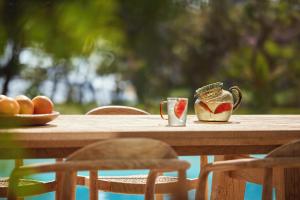 a wooden table with two cups and a bowl of fruit at Ikos Porto Petro in Portopetro