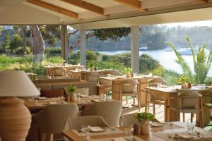 a restaurant with tables and chairs with a view of the water at Ikos Porto Petro in Portopetro