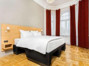a bedroom with a large bed with red curtains at Tribe Riga City Center in Rīga