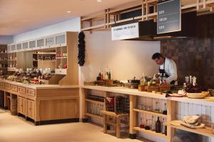 a man standing behind a counter in a kitchen at Ikos Porto Petro in Portopetro