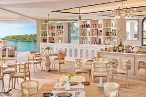 a restaurant with tables and chairs and a view of the water at Ikos Porto Petro in Portopetro