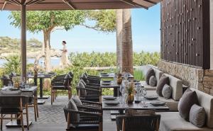 a restaurant with tables and chairs with a woman in the background at Ikos Porto Petro in Portopetro