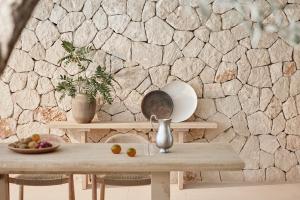 a table with a bowl of fruit and a stone wall at Ikos Porto Petro in Portopetro