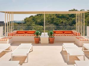 an outdoor patio with benches and orange pillows at Mercure Ambassador Jeju in Seogwipo