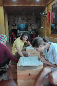 three women sitting at a table looking at a box at Hmong Wooden Home in Sa Pa +115 photos