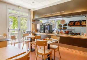 un restaurant avec des tables, des chaises et un comptoir dans l'établissement B&B HOTEL Le Puy-en-Velay, à Vals-près-le-Puy