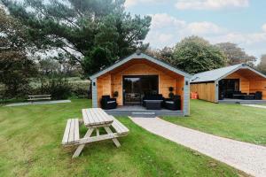 a wooden cabin with a picnic table in the grass at Riverside Retreats - Steamers Meadow in Gwinear