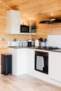 a kitchen with white cabinets and a stove top oven at Riverside Retreats - Steamers Meadow in Gwinear