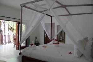 Kivuli Beach Resort Paje في باجي: غرفة نوم بسرير أبيض مع مظلة