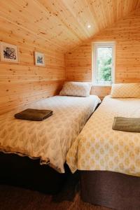 um quarto com 2 camas num chalé de madeira em Riverside Retreats - Steamers Meadow em Gwinear
