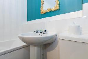 La salle de bains blanche est pourvue d'un lavabo et d'un miroir. dans l'établissement A gem nestled in the heart of Oxford with parking!, à Oxford