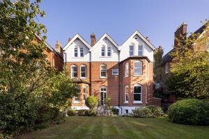an exterior view of a large brick house with a yard at Veeve - Courtside Charms in London