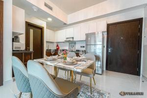 a kitchen with a table with chairs and a refrigerator at Lawnz-4 210 in Dubai