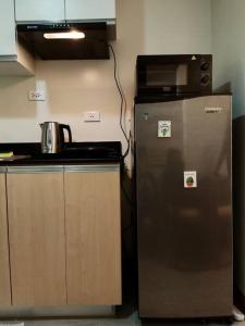 La cuisine est équipée d'un réfrigérateur en acier inoxydable et d'un four micro-ondes. dans l'établissement Cozy studio w/ Nintendo Switch, à Bacolod
