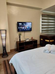 - une chambre avec un lit blanc et une télévision à écran plat dans l'établissement Cozy studio w/ Nintendo Switch, à Bacolod