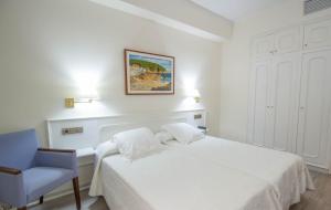 1 dormitorio blanco con 1 cama y 1 silla azul en Hotel Llafranch en Llafranc