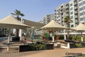 a group of tables with umbrellas in front of a building at Lawnz-4 210 in Dubai
