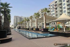 a large swimming pool with palm trees and buildings at Lawnz-4 210 in Dubai