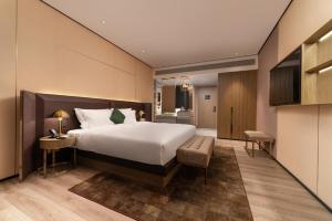 a hotel room with a bed and a desk and a chair at Echarm Plus Hotel - Foshan Smart New City Zhangcha Metro Station Branch in Foshan