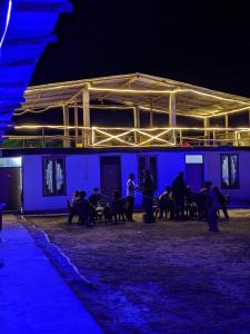 un groupe de personnes assises à l'extérieur d'un bâtiment la nuit dans l'établissement Damnbro Cafe & Stay KASOL, à Kasol