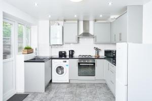 eine weiße Küche mit einer Waschmaschine und einem Geschirrspüler in der Unterkunft 3 Bedroom Home in Central Milton Keynes in Loughton