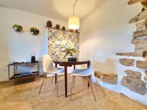 ein Esszimmer mit einem Tisch, Stühlen und einer Steinmauer in der Unterkunft Villa Pedra Natural Houses in Alvorge