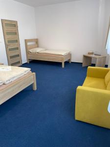 Cette chambre comprend deux lits, un canapé et une chaise. dans l'établissement Hotel U města Prahy Náchod, à Náchod