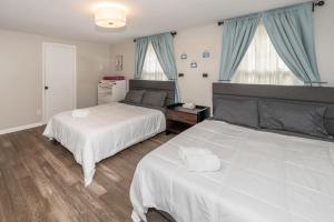 two beds in a bedroom with blue curtains at Centrally Located Luxury House in Ann Arbor