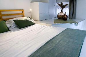 ein Schlafzimmer mit einem großen Bett mit weißer Bettwäsche und grünen Kissen in der Unterkunft Acacia Firenze - Giglio in Florenz