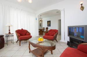 sala de estar con muebles de color rojo y TV en Villa Marcus - 3 Bedrooms large pool plus childs pool - Great for families en Puerto del Carmen