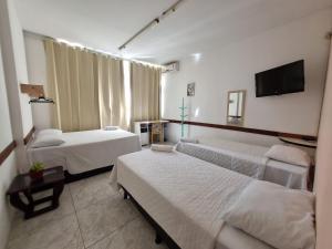 a hotel room with two beds and a flat screen tv at Nomads Hostel Multicultural & Coworking in Salvador +37 photos