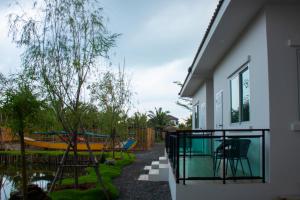 a house with a balcony with a boat in the yard at Yunoya Riverside Villa in Samut Songkhram