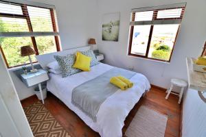 um quarto com uma cama com uma almofada amarela em Kykmar Beach House em Stilbaai