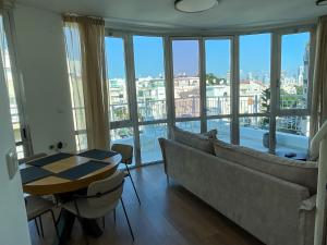 een woonkamer met een bank, een tafel en ramen bij David Frishman Residence - Sea view penthouse in Tel Aviv