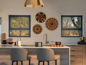 a kitchen with two windows and a counter with chairs at Nomads Den Luxury Villa with Riverbed View in Hoedspruit