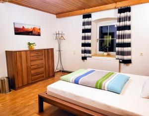 a bedroom with a bed and a dresser and a window at schöne, vollausgestattete 90m2 Wohnung mit drei Zimmern am Land 