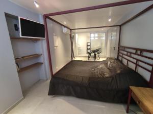 een kleine slaapkamer met een bed en een televisie bij Chambre Secret Room, Riad 3 Couple only au village naturiste in Cap d'Agde