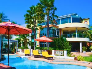 einem Pool mit Stühlen und Sonnenschirmen vor einem Gebäude in der Unterkunft Vartika Resovilla Kuiburi Beach Resort and Villas in Kui Buri