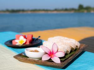 une assiette de nourriture avec une fleur sur une table dans l'établissement Mekong Bird Resort & Hotel, à Stœ̆ng Trêng