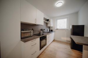 コブレンツにあるCoblenz Suites - Design Apartment Cityの白いキャビネットと木製の床を備えたキッチン