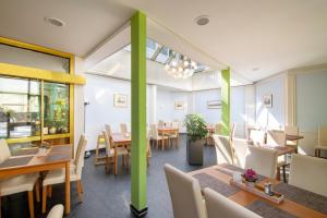 ein Restaurant mit Holztischen und -stühlen und grünen Säulen in der Unterkunft Seehotel Grunewald in Berlin