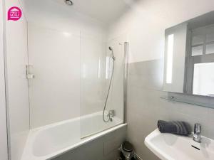 La salle de bains blanche est pourvue d'une douche et d'un lavabo. dans l'établissement Le Grand'rue by iZiLi - Centre Ville - Confort, à Poitiers