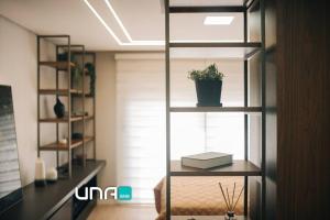佩洛塔斯Loft com sacada, lareira e garagem no Parque Una的书架上放着盆栽的房间