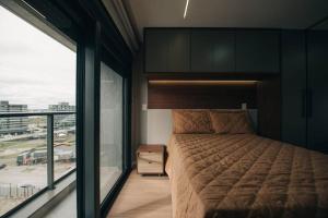 a bedroom with a bed and a large window at Loft com sacada, lareira e garagem no Parque Una in Pelotas