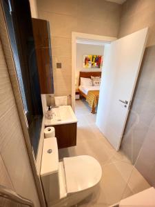 a bathroom with a toilet and a sink and a bed at Fajara Residence in Fajara