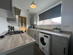 uma cozinha com uma máquina de lavar roupa e uma janela em Alexander Apartments West Harton em South Shields