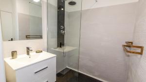 a white bathroom with a sink and a shower at Ti jacques location - Saint-Gilles les bains - studio pour 2 personnes in Saint-Paul