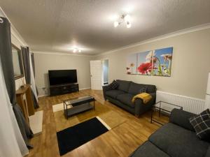 a living room with a couch and a tv at President Road- A Spacious and homely four bed house by Catchpole Stays in Lexden