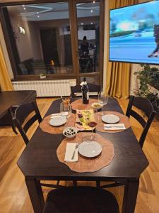 バンスコにあるTerra Complex-D4-Balkan private apartment - Golf & Skiingの木製テーブル(皿、ワイングラス付)、テレビが備わります。